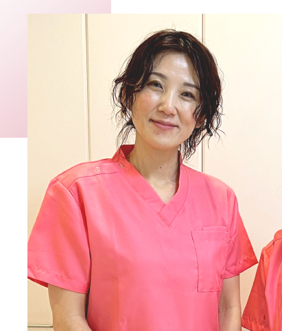 Smiling female healthcare worker wearing pink scrubs, posing indoors.